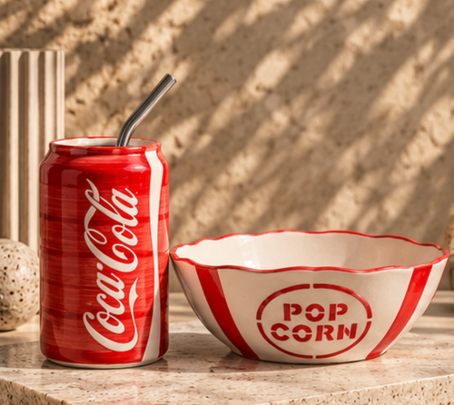 Coca-Cola ceramic tumbler and popcorn bowl set on stone surface