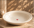 Cream pasta plate with red heart detail on a sunlit countertop
