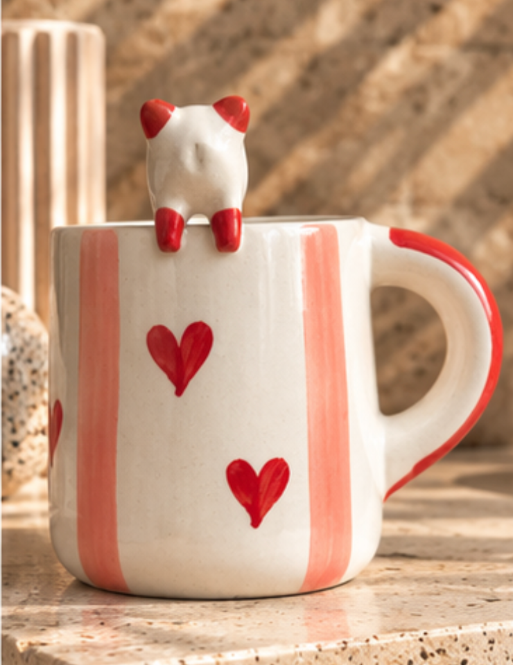 Close view of cat figurine and heart details on a pink striped mug