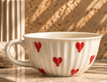 Side view of cream Heart Tea Cup with red hearts and curved handle